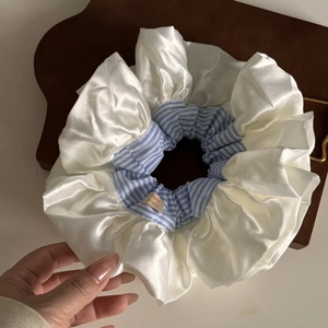Oversized satin hair scrunchie with blue stripes and handmade label on wood background