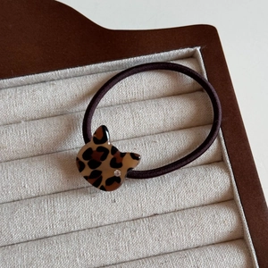 Detail of leopard print cat charm hair tie with crystal accent on a jewelry tray