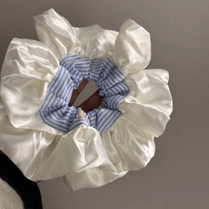 Detailed view of oversized satin scrunchie with blue stripes and lace edge