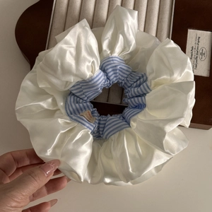 Detail showing oversized cream satin and blue striped scrunchie with handmade tag