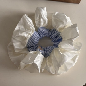 Macro detail of oversized cream satin scrunchie with blue stripes and handmade label