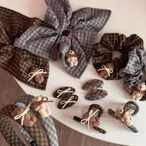 Detailed view of plaid scrunchies and hair clips with plush bears and ribbon bows