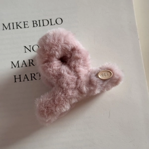 Gros plan détaillé d'une pince à cheveux en peluche rose avec étiquette ovale EGG