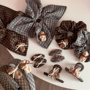 Close-up of vintage plaid hair accessories featuring plush bear dolls and bowknot details