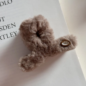 Gros plan sur la pince à cheveux en peluche douce avec logo ovale pour l'hiver