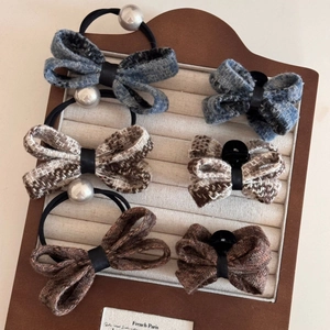 Close-up of elegant tweed bow hair clips and scrunchies featuring pearl accents