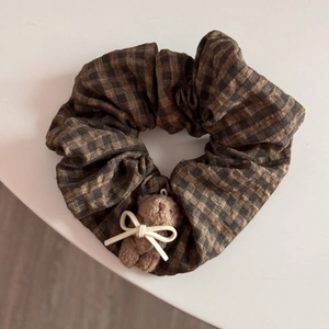 Close-up of brown plaid scrunchie with a cute plush bear and bow on white background