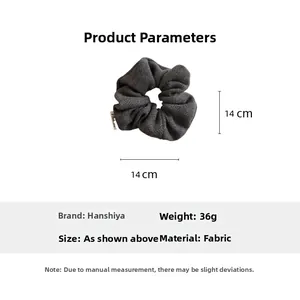 Detailed view of grey herringbone wool scrunchie showing 14cm diameter and fabric texture