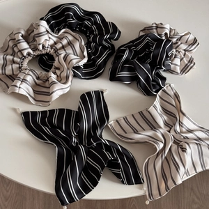 Detail of striped silk scrunchies with pearls on a white table in minimalist style