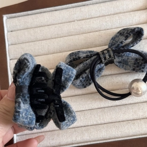 Detailed close-up of blue tweed bow hair clip and elastic hair tie with large silver pearl