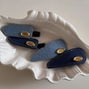 Set of four premium denim fabric hair clips with gold oval metal accents in a white tray