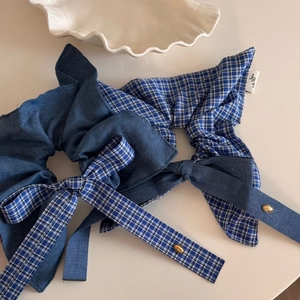Detailed shot of blue plaid and denim bow hair scrunchies with elegant gold metal tags