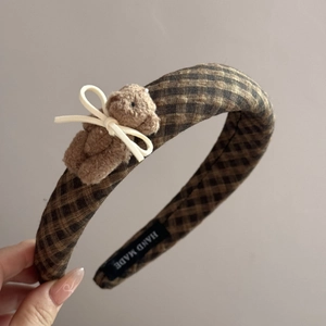 Detail of handmade plaid headband featuring a cute brown plush bear with a ribbon bow