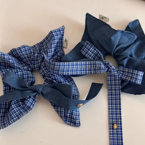 Close-up of blue plaid and denim bow hair scrunchies with elegant gold love charms