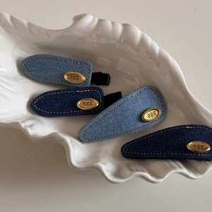 Set of four denim fabric hair clips in blue tones with oval gold metal egg labels