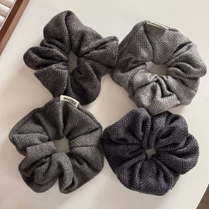 Close-up of four wool hair scrunchies featuring classic grey herringbone pattern texture