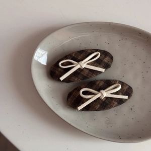 Detailed view of two vintage plaid hair clips with delicate cream-white rope bows