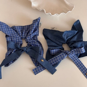 Detailed shot of blue plaid scrunchies with bow ribbons and golden metal buttons