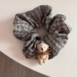 Detailed view of plaid scrunchie with cute cream plush bear and brown ribbon bow