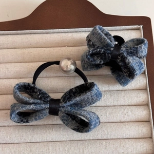 Detailed shot of blue tweed bow hair clip and elastic tie on a jewelry display tray