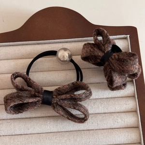 Close-up of winter tweed bow hair clip and elastic tie set with metallic bead detail