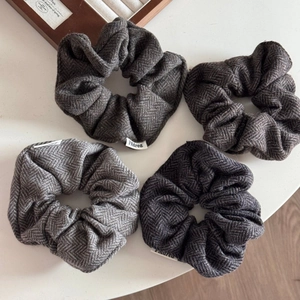 Close-up of four herringbone pattern wool scrunchies in shades of grey and brown