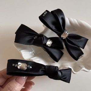 Détail de barrettes nœuds en satin noir élégantes ornées de strass en cristal brillant