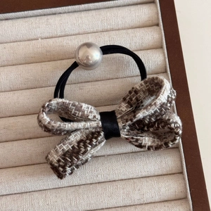Detail of tweed bow hair tie with grey decorative bead and elastic black rubber band