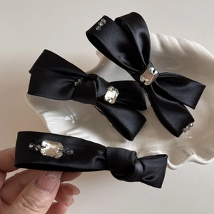 Détail de barrettes à nœuds en satin noir avec strass étincelants et perles en cristal