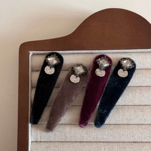 Detailed view of four velvet hair clips with square rhinestones and silver letter charms