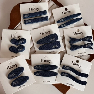 Detailed set of denim blue hair clips in various shapes on a branded display card