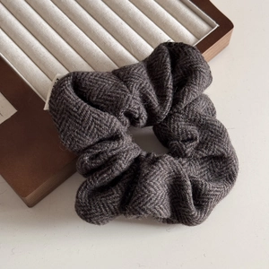 Detailed view of dark grey herringbone wool hair scrunchie with soft fabric texture