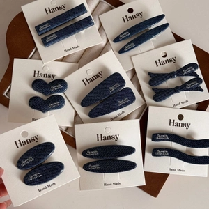 Denim fabric hair clips set with silver lettering on white display cards for styling