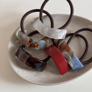 Cinq chouchous géométriques en acétate aux motifs écaille et marbre sur un plateau chic