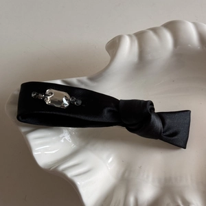 Détail d'une pince à cheveux en satin noir avec strass sur plateau en coquille