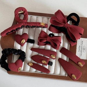 Elegant red bow hair clips and velvet hairpins with golden labels for New Year hairstyles