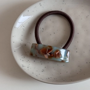 Vue macro d'élastique en acétate écaille avec logo France Handmade doré sur plateau céramique