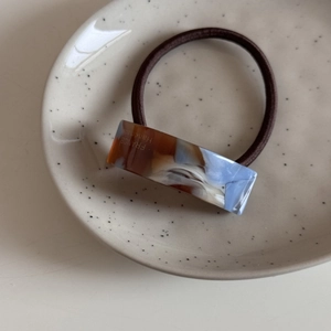 Détail d'un élastique à cheveux en acétate fait main avec motif marbré bleu sur plateau