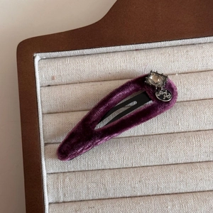Detailed macro view of purple velvet hair clip with square rhinestone and silver charm