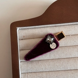 Detail of vintage velvet hair clip with a square gemstone and handmade metal tag