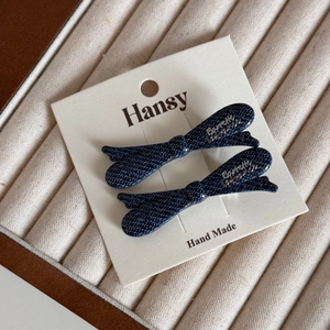 Detail of denim blue bow hair clips with silver letter label on premium display card