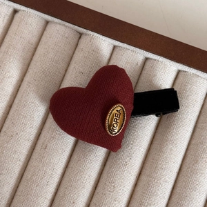 Close-up of heart-shaped burgundy fabric hair clip with a gold KOREA metal label