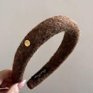 Detail of coffee brown wool hairband showing plush texture and gold buckle engraving
