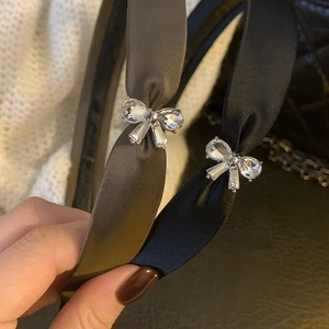 Dettaglio di cerchietti in raso con fiocchi di strass nei colori nero e marrone