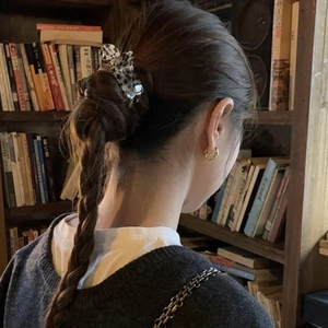 Elegant woman wearing a tortoiseshell hair claw and golden twist hoop earrings in a library