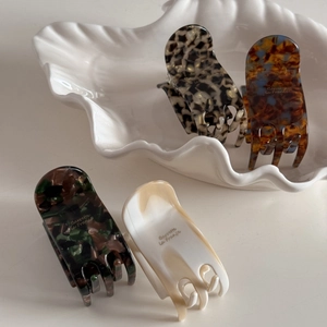 Detailed macro view of four acetate hair claws in various elegant marble and tortoiseshell patterns