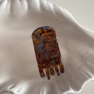 Detailed macro view of acetate tortoise shell hair claw clip with golden logo text