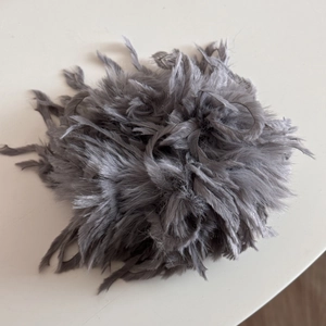 Detailansicht des weichen, grauen Feder-Haargummis mit voluminöser und flauschiger Textur