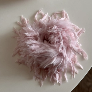 Detailansicht des rosa Feder-Haargummis mit flauschiger Textur für Pferdeschwänze
