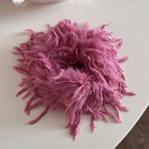Makroaufnahme von rosa Feder-Haargummi für Pferdeschwanz zeigt weiche Textur und Material